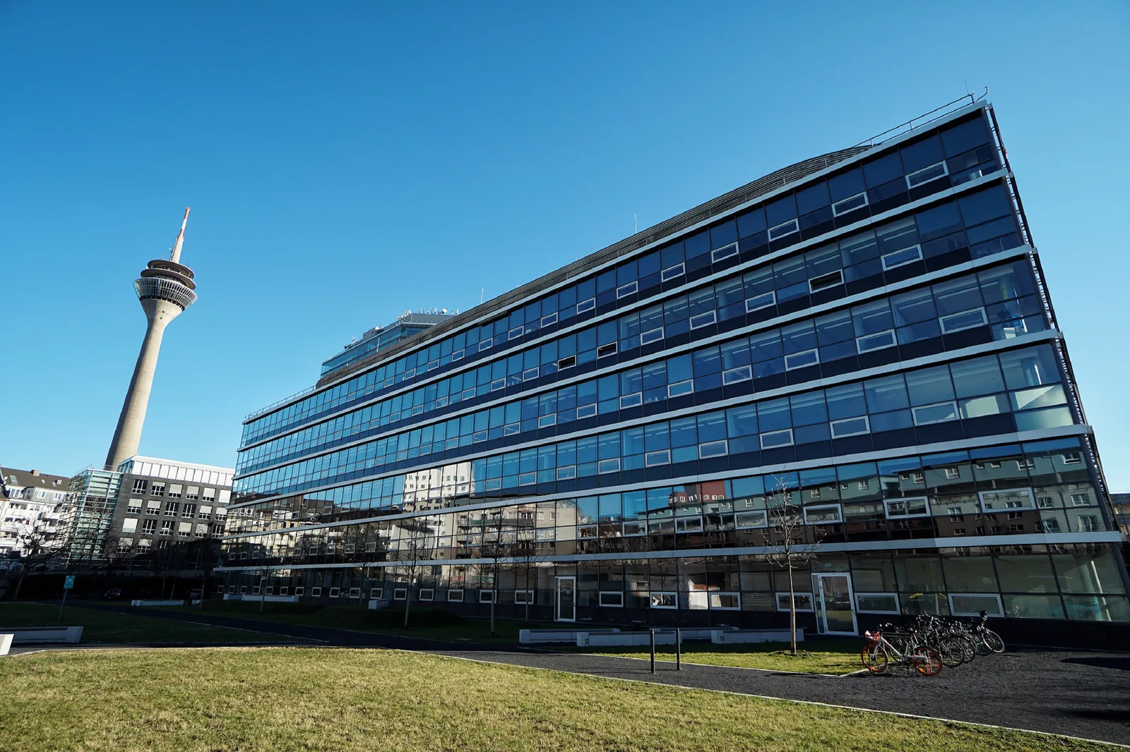 The StepStone office building in Düsseldorf, with the Rheinturm tower behind it under a clear blue sky.